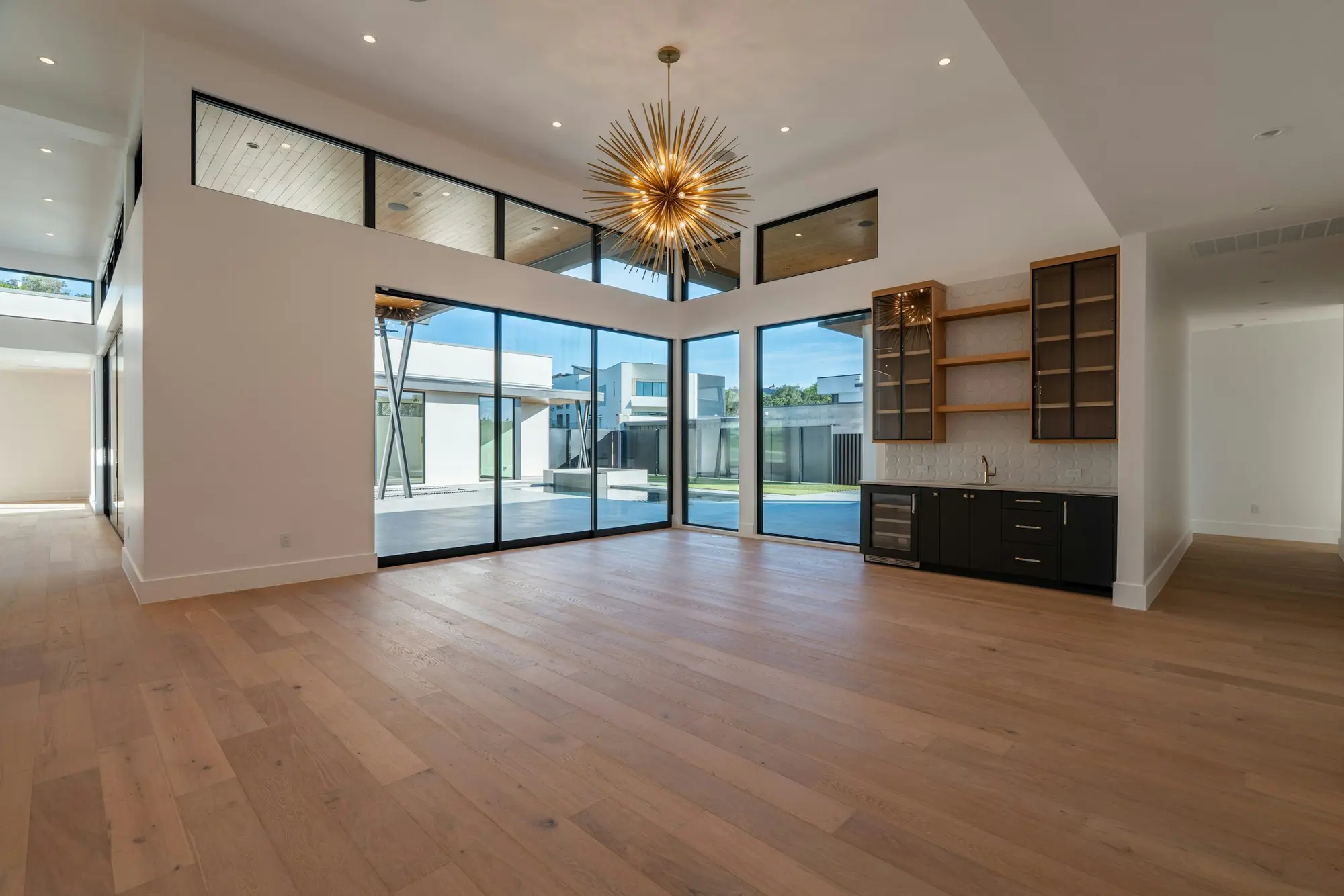 Wide-plank white oak floor running through an open living room toward floor-to-ceiling windows