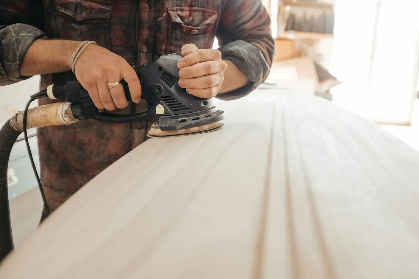 Edge-sanding an oak floor with an orbital sander connected to dust containment