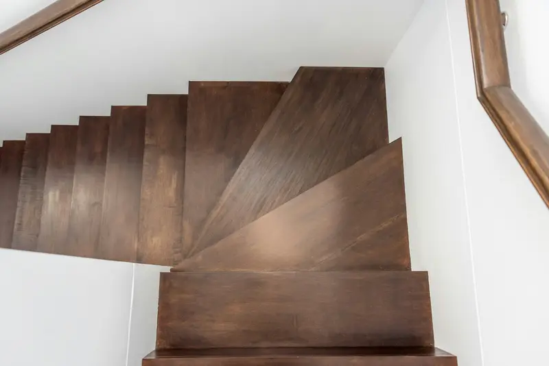 Dark-stained oak treads with white risers on a turning staircase